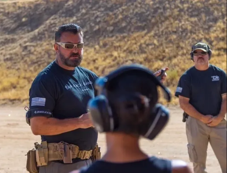 Instructors coaching a student at an outdoor shooting range
